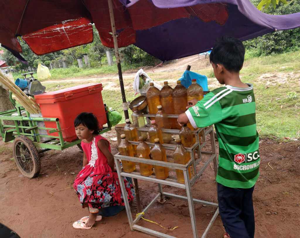 Two kids on the road in Siem Reap selling Gasoline to tuk tuk drivers